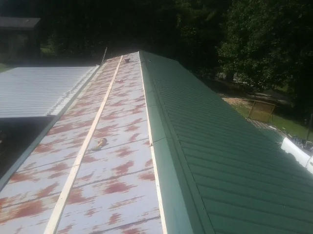 Old rusted panels beside newly installed green metal roofing — Wind Damage Roof Repair by Roofing Brothers in Piedmont