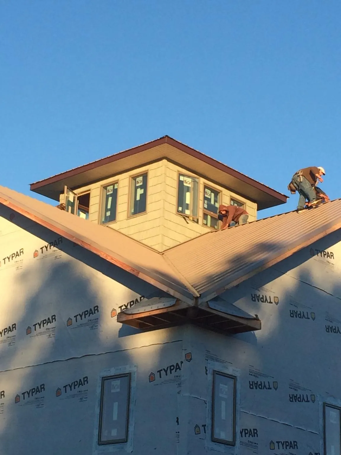 Roofers working around a rooftop cupola on a new metal roof at sunset — Roof Waterproofing in Piedmont by Roofing Brothers